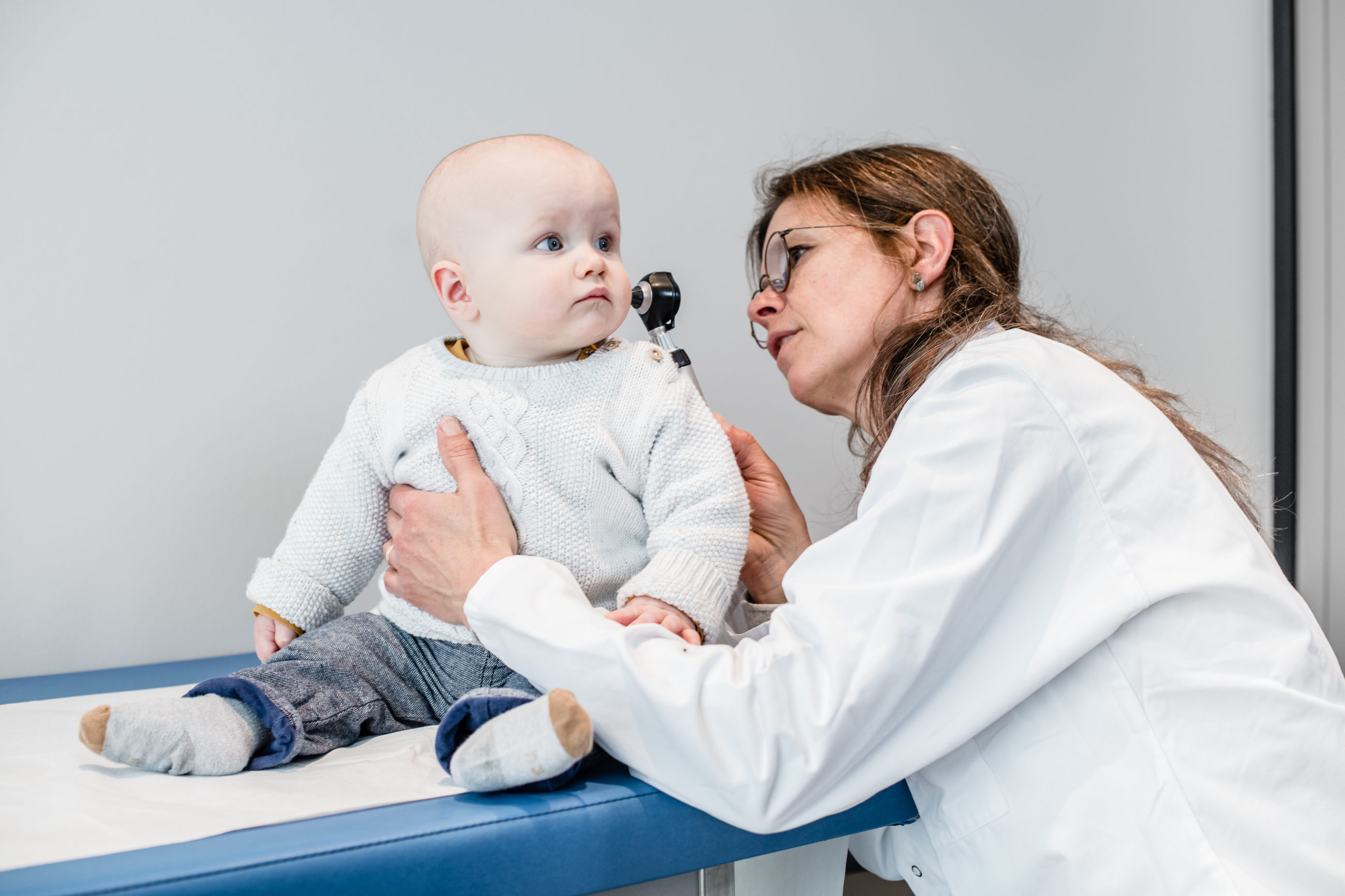 Medecin qui ausculte un bébé à la Garde Pédiatrique des Eaux-vives